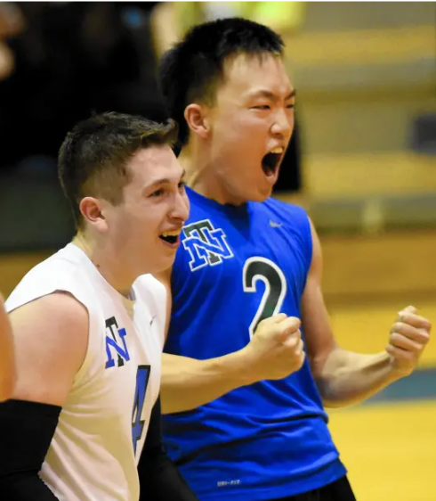 Deux volleyeurs célébrant avec enthousiasme sur le terrain, l'un portant un maillot blanc et l'autre portant un maillot bleu, véhiculant l'enthousiasme et l'esprit d'équipe.