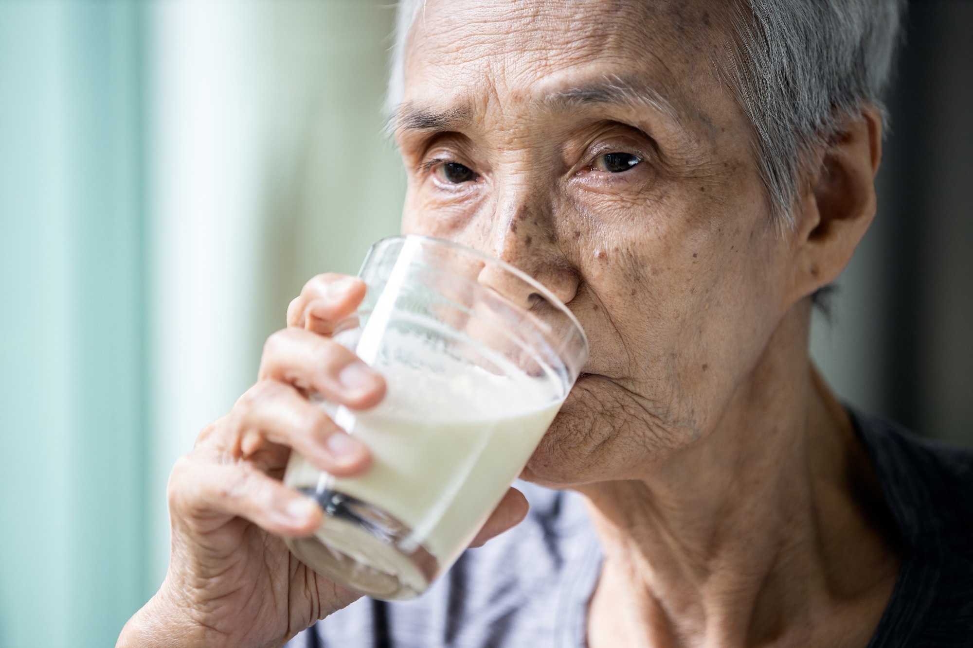 Femme &acirc;g&eacute;e asiatique buvant du lait frais et chaud dans un verre le matin &agrave; la maison