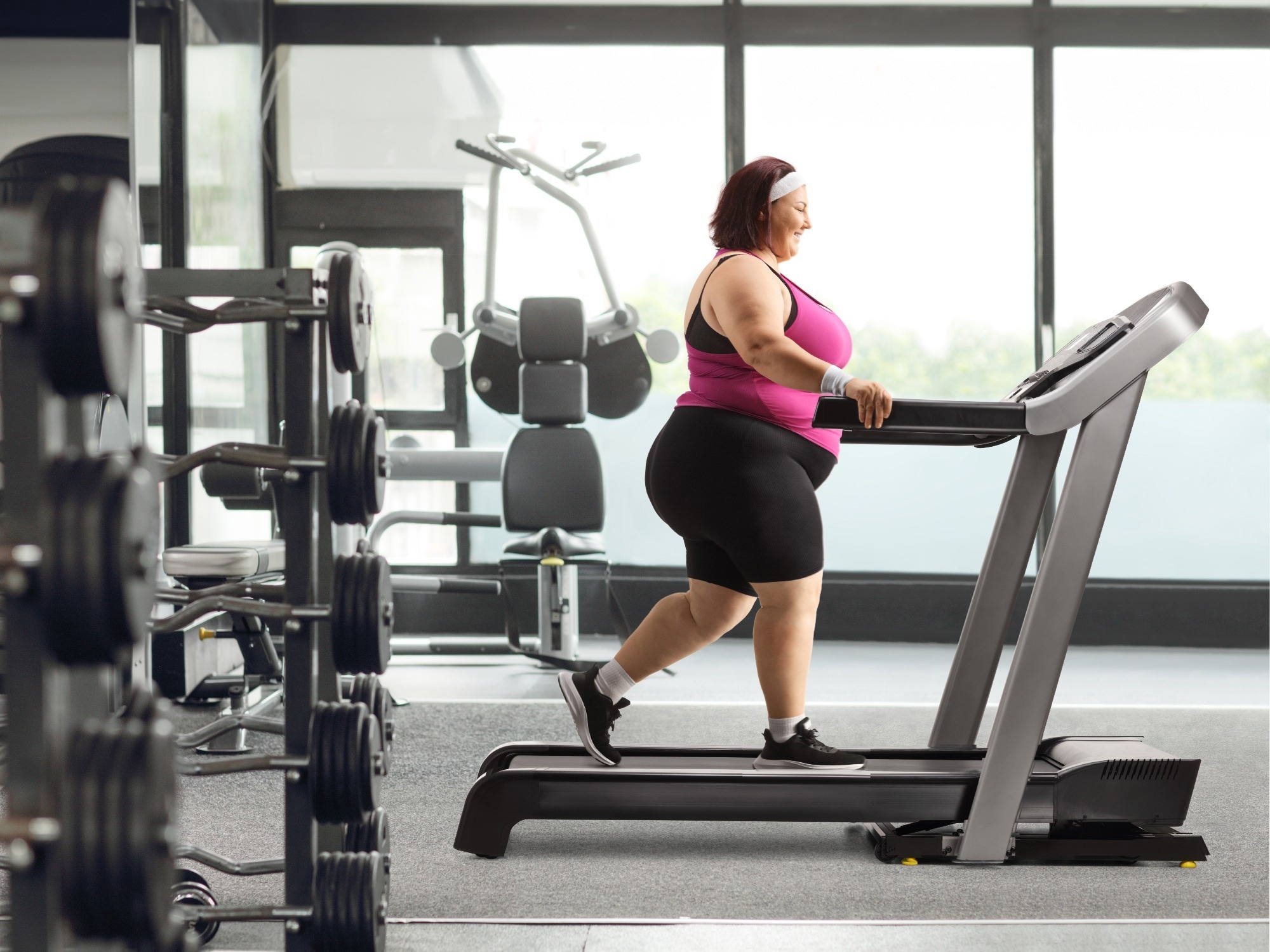 Femme en surpoids marchant sur un tapis roulant &agrave; la salle de sport