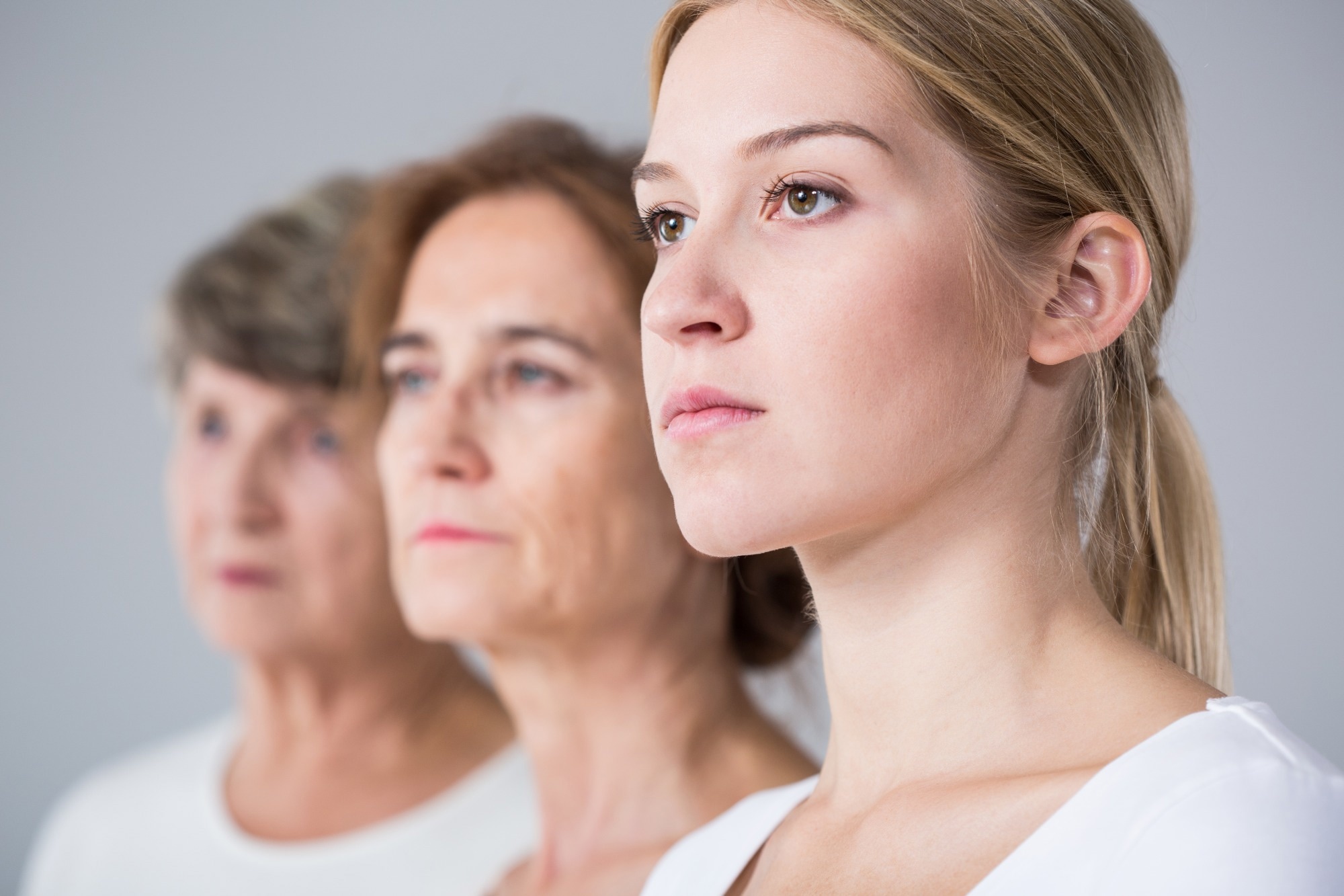 Image of three generation of women stood in a line leading away from camera.